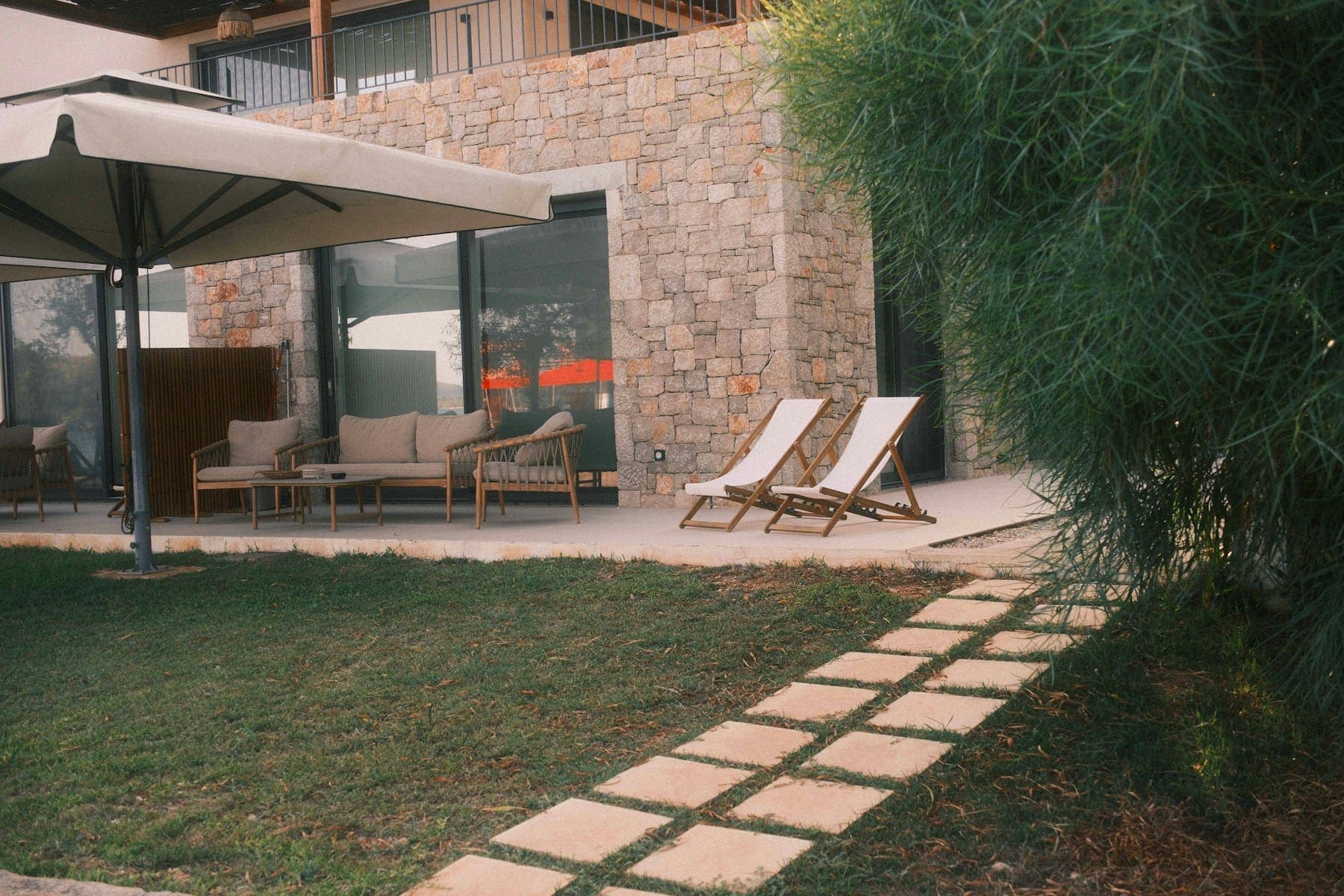 Stone terrace with loungers, stepping-stone path and soft planting