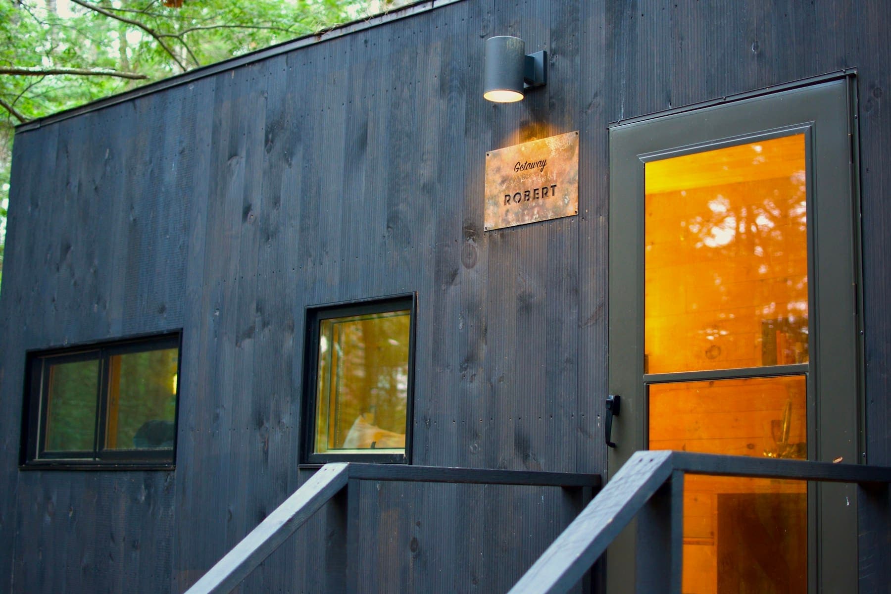 Charcoal timber cladding with a glazed door glowing warmly