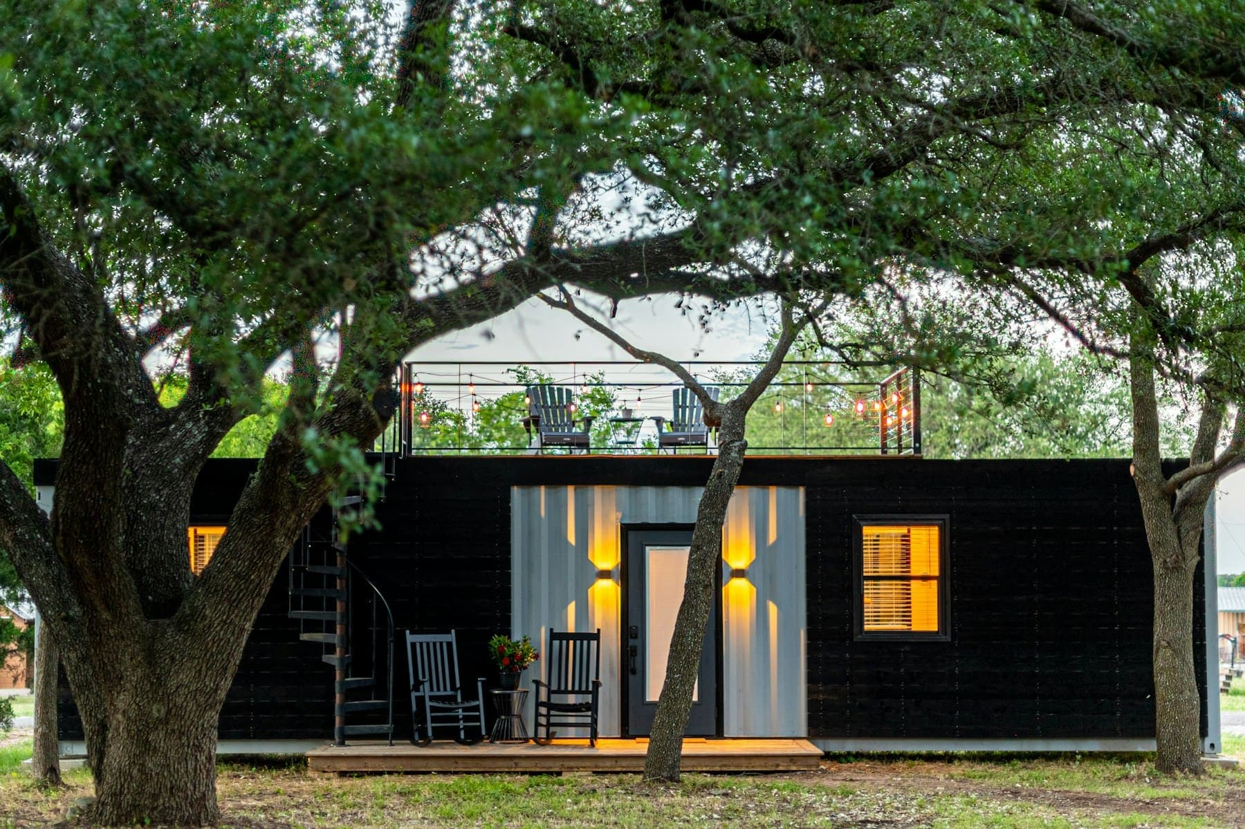 Dark timber building with glowing windows set among trees