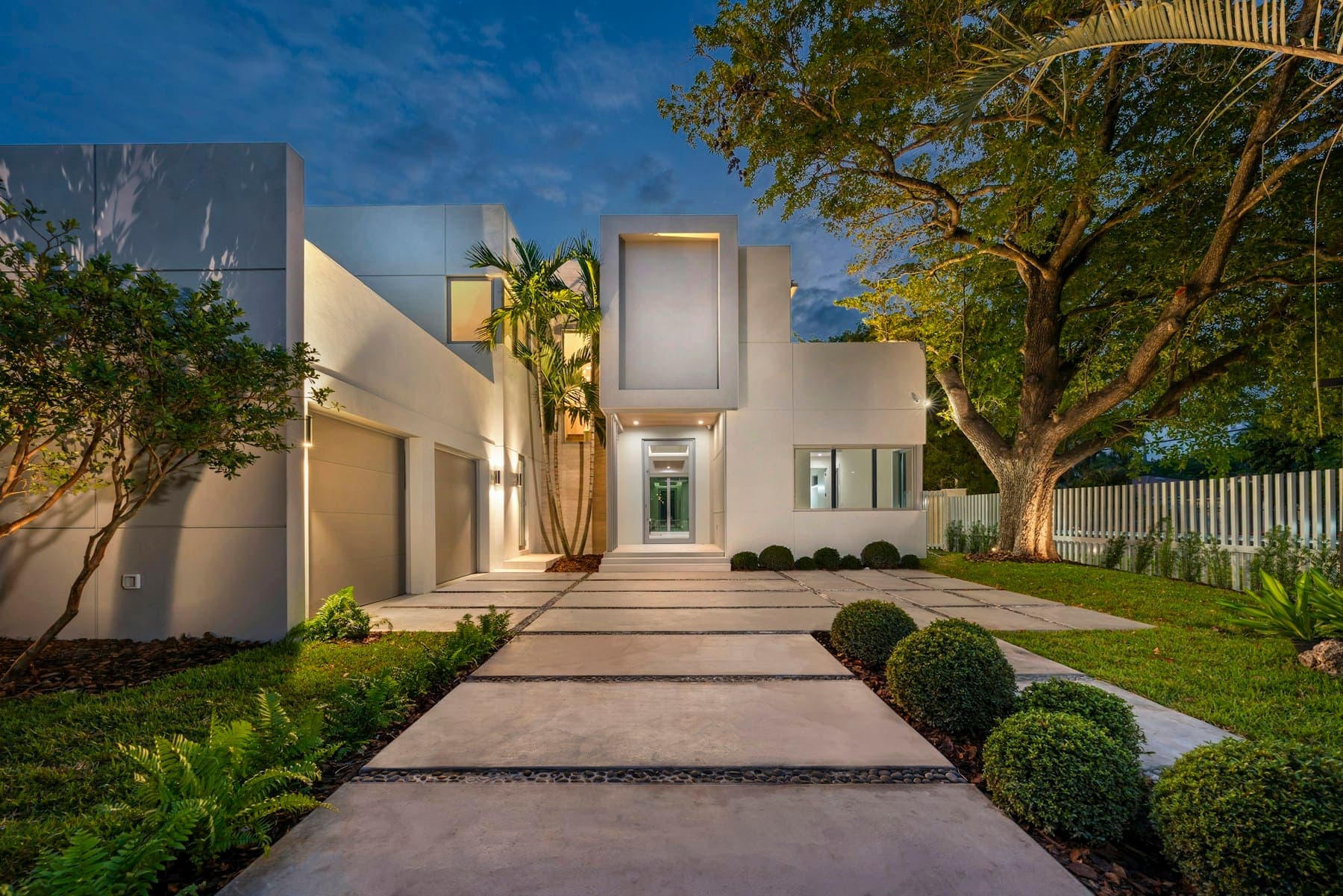 Large-format paving path lit at dusk leading to a modern house