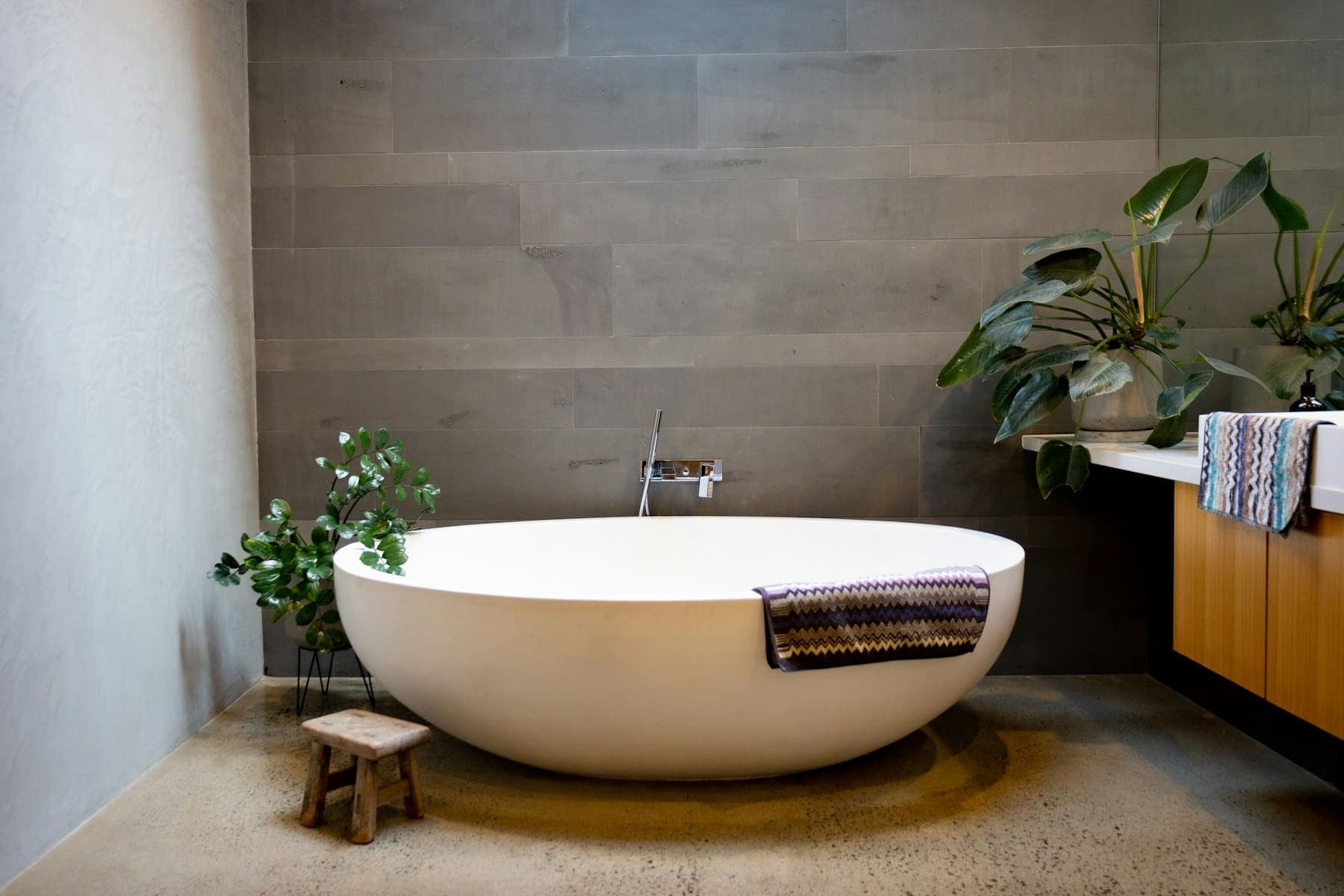Round stone bath on a warm concrete floor surrounded by plants