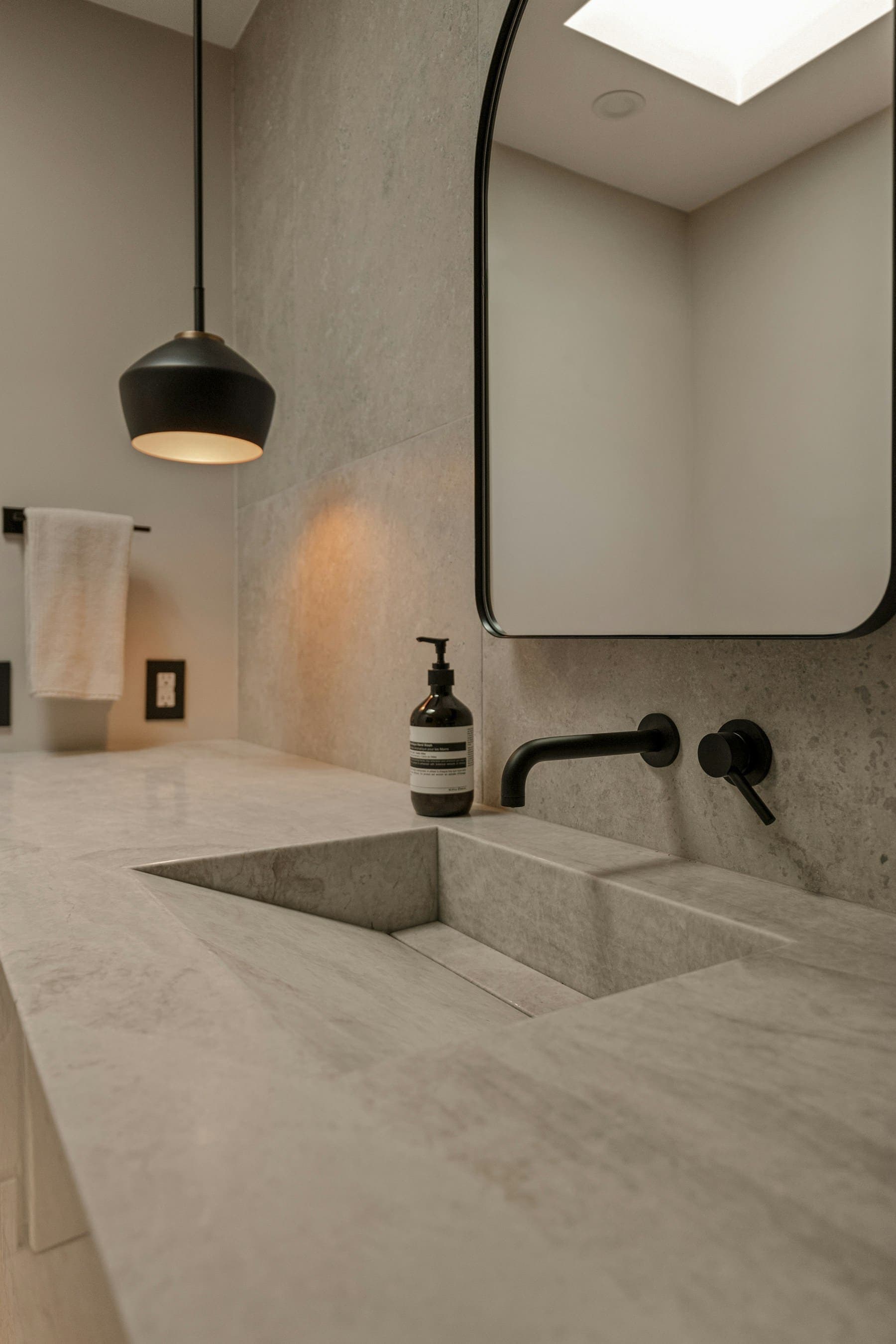 Integrated stone basin with a wall-mounted black tap